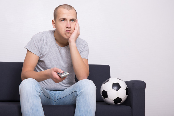 bored soccer fan with ball watching game on tv - Valokuva, kuva