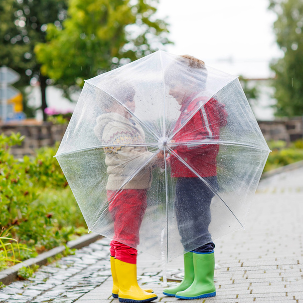 Two little kid boys with big umbrella outdoors - Fotó, kép