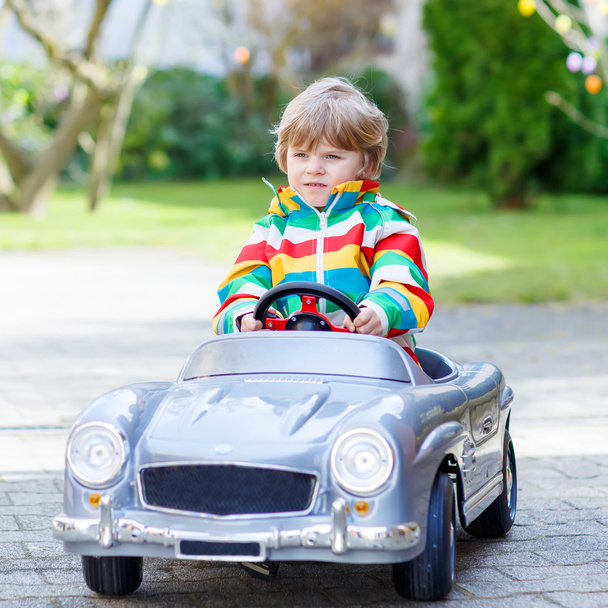 Pequeno menino pré-escolar dirigindo grande brinquedo velho carro vintage, ao ar livre
 - Foto, Imagem