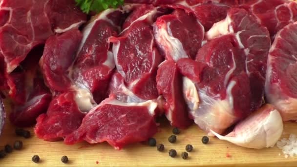 Νωπό βόειο κρέας σε ξύλινη σανίδα με σκόρδο και κρεμμύδια - Πλάνα, βίντεο