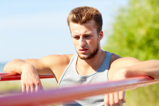 young man exercising on parallel bars outdoors - Foto, Bild