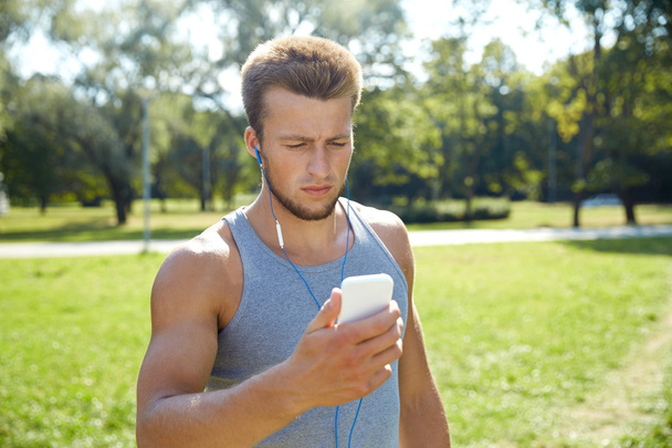 young man with earphones and smartphone at park - Foto, Bild