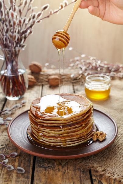 Flowing honey on stack of homemade traditional pancakes with nuts - Fotó, kép