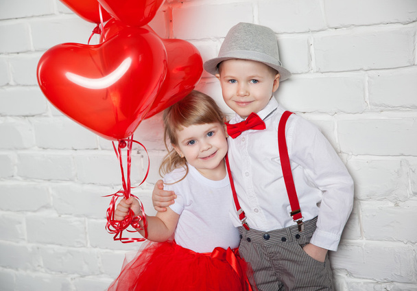 Little kids holding and picking up heart balloons. Valentine's Day and love concept, on white background - Fotoğraf, Görsel