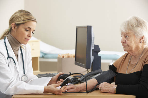 Doctor taking woman's blood pressure - Foto, Imagem