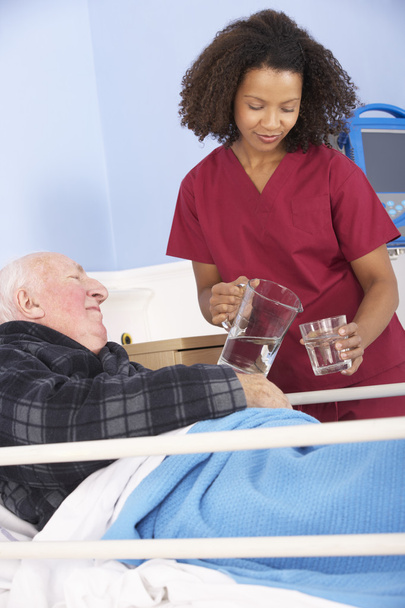 Nurse giving glass of water to man - Photo, image