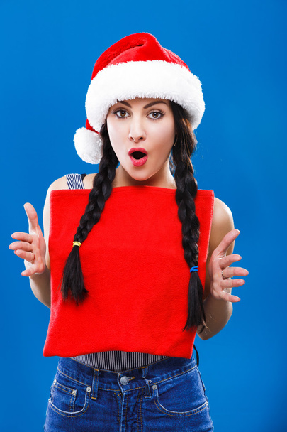 Здивована молода дівчина з червоною різдвяною сумкою
 - Фото, зображення