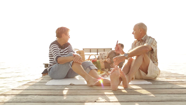 Cuatro personas mayores disfrutando de un picnic en embarcadero
 - Imágenes, Vídeo