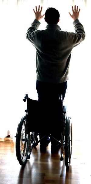 giovane in piedi con la sedia a rotelle vicino alla finestra
 - Foto, immagini