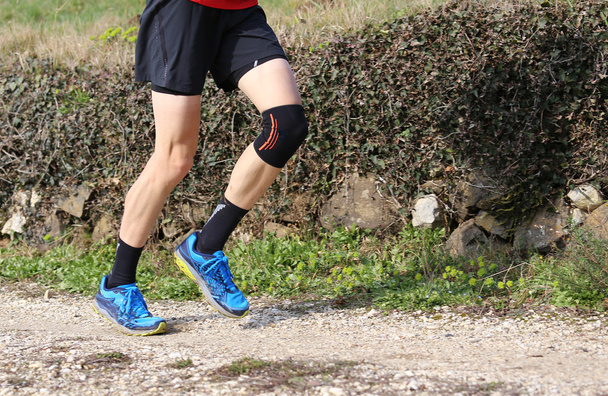 corredor de cross-country durante la carrera con su rodilla envuelta por un
  - Foto, Imagen