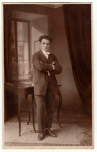 Vintage photo shows young man poses in the room. Antique black & white studio portrait. - Photo, Image