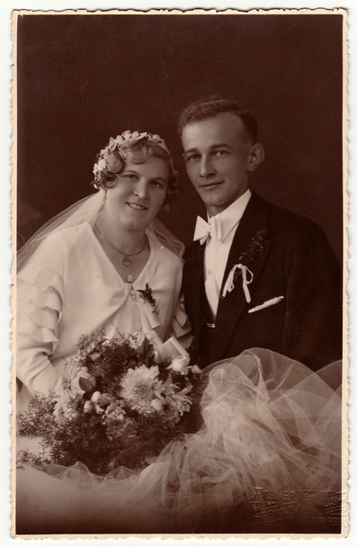 Vintage φωτογραφίες του νεόνυμφων με Γαμήλια ανθοδέσμη. Νύφη φοράει γαμήλια κόμμωση πέπλο. Νεόνυμφος φορά σικ ρούχα, λευκό παπιγιόν. Μαύρο & άσπρο αντίκες στούντιο πορτρέτου. - Φωτογραφία, εικόνα