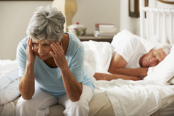 Worried Senior Woman Sits On Bed - Foto, afbeelding