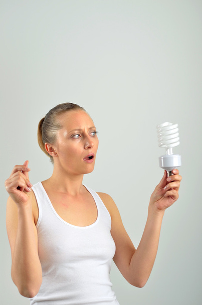 schöne junge Frau hat eine Idee mit dem Halten einer Glühbirne - Foto, Bild