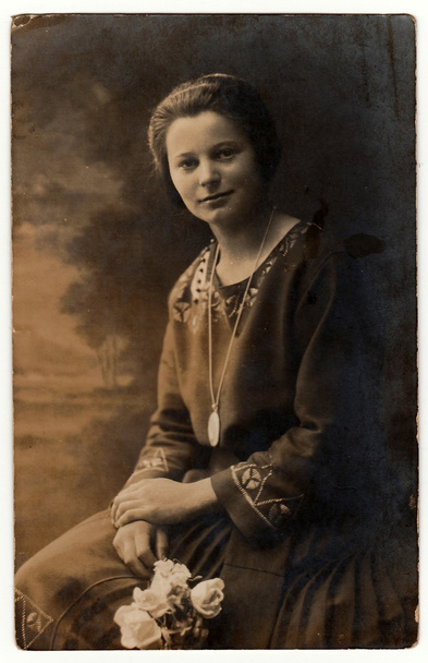Vintage photo shows woman holds white roses. Photo with dark sepia tint. Black & white studio portrait. - Photo, Image