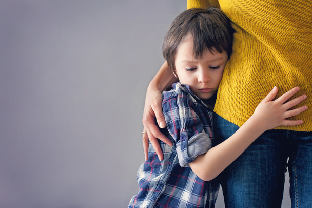 Sad little child, boy, hugging his mother at home - Foto, afbeelding