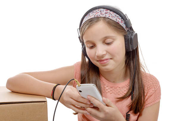 preteen girl listening to music with his smartphone, on white - Photo, Image