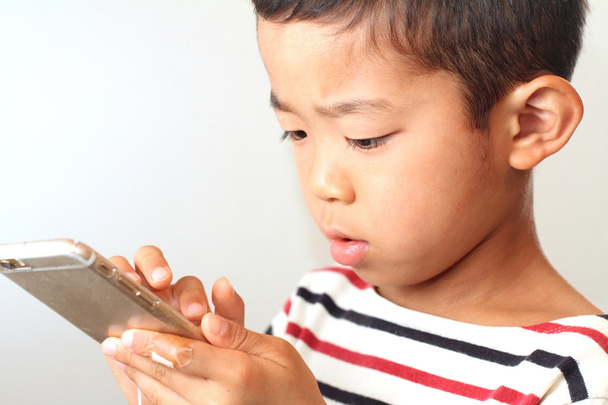 Japanese boy using a smart phone (6 years old) - 写真・画像