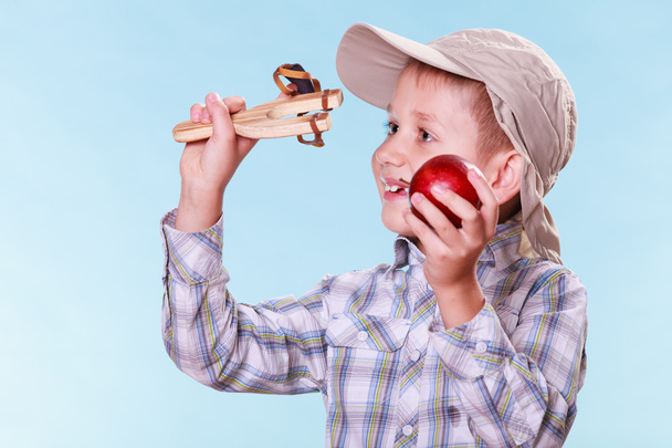 Young boy use sling shot hold apple. - Photo, image
