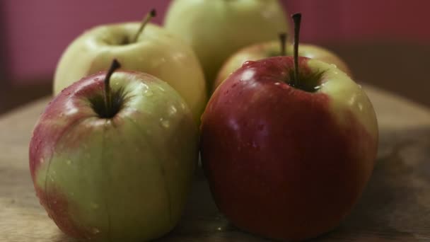 Materiał zbliżenie świeży i mokre zielony i czerwony jabłek mieszanych leżą na boardzie drewniany, który się kręci wokół. - Materiał filmowy, wideo