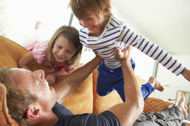 Father And Children Lying On Sofa At Home - Foto, imagen