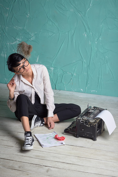 Joven mujer de negocios con estilo, máquina de escribir retro, espacio de arte azul, oficina
 - Foto, imagen