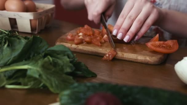 Слідкування за кадром жіночих рук з французькими цвяхами розрізають помідор на скибочки для приготування салату, зелені та овочів лежать на столі
 - Кадри, відео