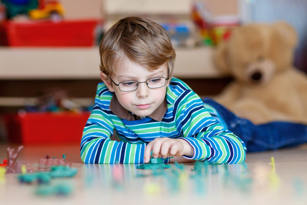 Dziecko, chłopiec bawi się zabawkami żołnierzy pomieszczeniu w przedszkolu - Zdjęcie, obraz