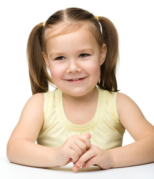 Happy little girl sits at a table and smile - Photo, Image