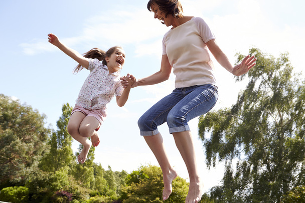 Mother And Daughter Bouncing On Trampoline - Foto, immagini