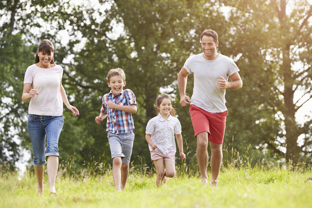 Smiling Family Running Across Summer Field - Foto, Imagem