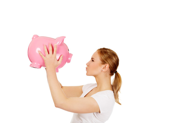 Happy young woman kissing a piggybank - Photo, image