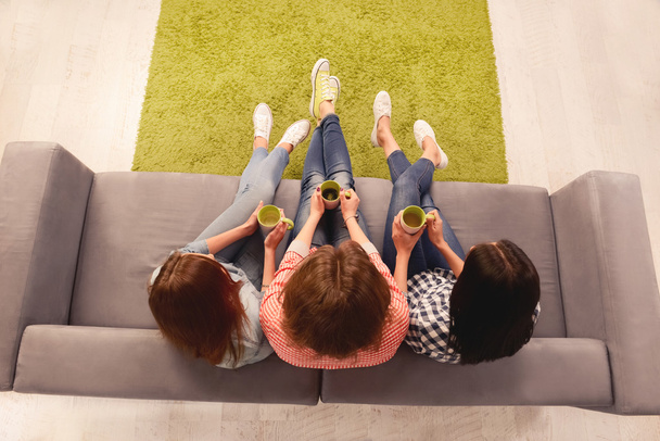 Top view photo of three women sitting on couch with cups - Photo, Image