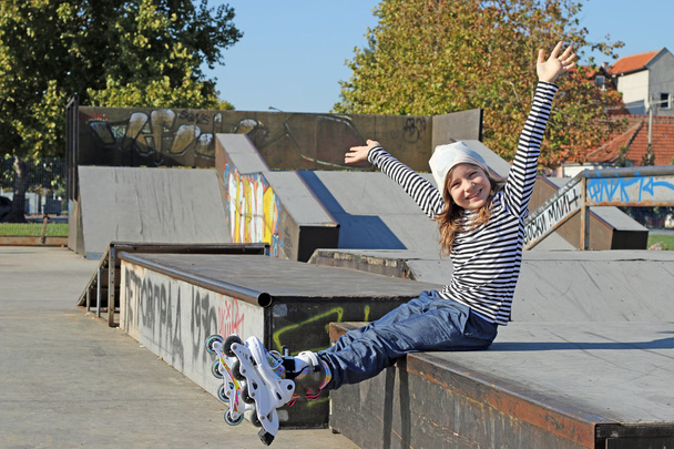 fröhliches kleines Mädchen mit Rollschuhen Spaß auf Spielplatz - Foto, Bild