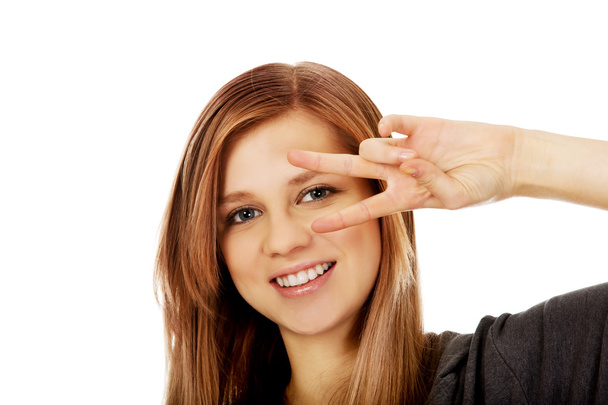 Teenage woman with victory sign on eye - Fotoğraf, Görsel