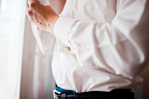 A young man wearing a cuff link, groom preparing for the wedding - 写真・画像