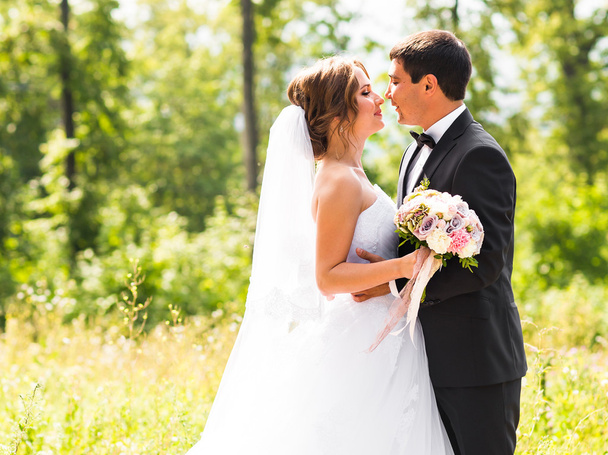 Young wedding couple enjoying romantic moments outside on a summer meadow - Photo, Image