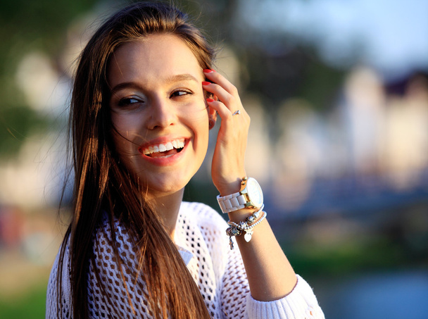 Retrato de una joven y bella mujer sonriente. Retrato de cerca de una joven y hermosa modelo posando al aire libre
. - Foto, Imagen