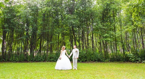 Young wedding couple enjoying romantic moments outside on a summer park - Photo, Image