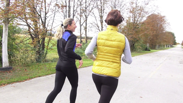 two women jogging in autumn - Кадри, відео
