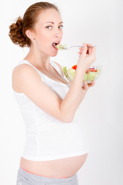Young pregnant woman eating fresh salad - Zdjęcie, obraz