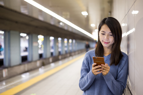 Kobieta za pomocą telefonów komórkowych w stacji metra - Zdjęcie, obraz