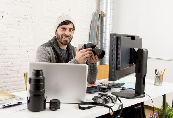 молодий привабливий прес-фотограф тримає фотоапарат, переглядаючи свою роботу на офісному столі редактора
 - Фото, зображення