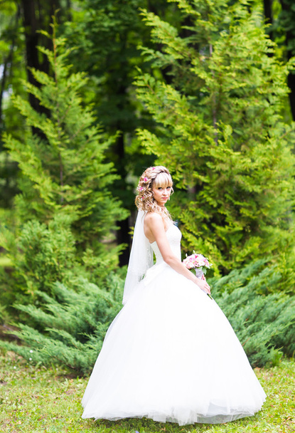 Pięknej narzeczonej z wesele bukiet kwiatów na świeżym powietrzu w parku. - Zdjęcie, obraz