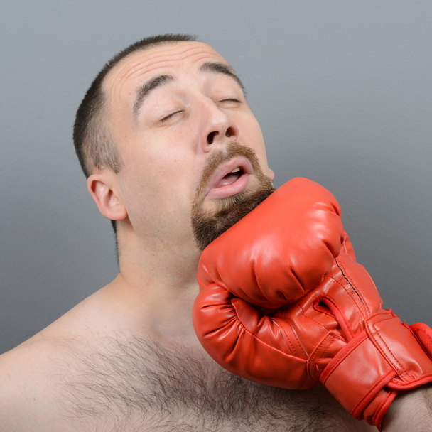 Portrait of funny fat boxer getting punch in face against gray b - Фото, зображення