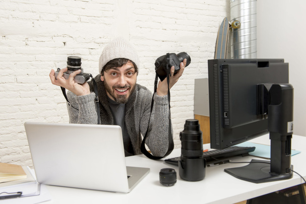 junger attraktiver Pressefotograf mit Fotokamera beim Betrachten seiner Arbeit auf dem Schreibtisch der Redaktion - Foto, Bild