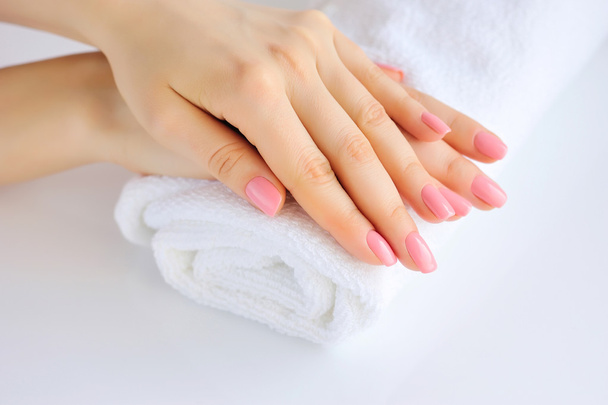 Hands of a woman with pink manicure are on a towel - Foto, Imagem