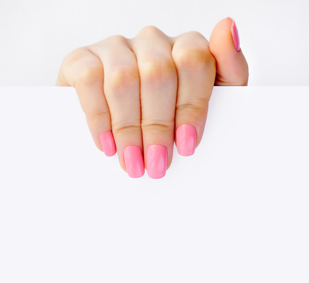 Hand of a woman with pink manicure holding white empty paper - Photo, Image