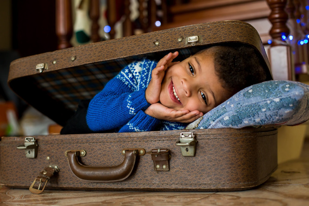 Χαμογελαστό παιδί τοποθέτηση μέσα σε βαλίτσα. - Φωτογραφία, εικόνα