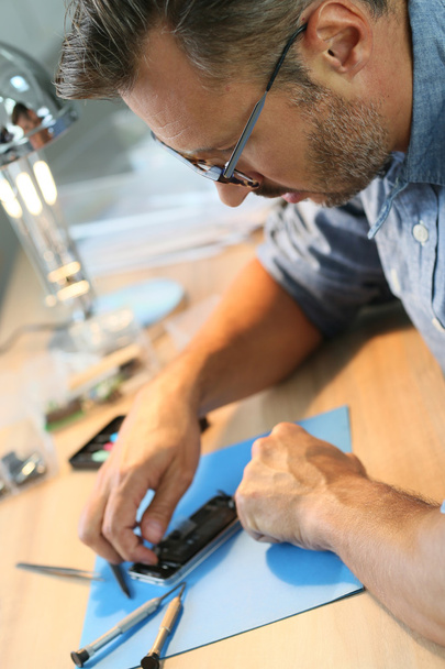 Mann repariert kaputtes Smartphone - Foto, Bild